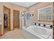 Bathroom highlighting a large soaking tub and tiled shower with glass enclosure, and a decorative window at 34827 E 7Th Ave, Watkins, CO 80137