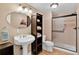 Cozy bathroom with tiled floors, pedestal sink, toilet, and a glass door shower, plus a storage cabinet at 34827 E 7Th Ave, Watkins, CO 80137