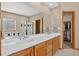 Bathroom showcasing double sinks with a wide mirror, bright white countertops, and walk-in closet access at 34827 E 7Th Ave, Watkins, CO 80137