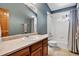 Bathroom with modern sink, white tile and wooden door. Features an overhead shower and large mirror at 34827 E 7Th Ave, Watkins, CO 80137