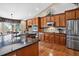 This kitchen features stainless steel appliances, wooden cabinets, tile backsplash, and granite countertops at 34827 E 7Th Ave, Watkins, CO 80137