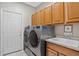 Efficient laundry room equipped with modern washer and dryer, countertop and storage, next to a rear entry door at 34827 E 7Th Ave, Watkins, CO 80137