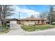 A single story home featuring a brick facade, mature trees, a detached garage and long driveway at 4395 E Arapahoe Pl, Centennial, CO 80122