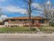 Charming brick home featuring a well-kept lawn, a wooden porch, and a welcoming entrance at 4395 E Arapahoe Pl, Centennial, CO 80122