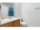 Clean half bath featuring a toilet and sink with a bright shower and curtain visible in the mirror at 32 Whitehaven Cir, Highlands Ranch, CO 80129