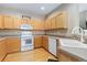 Eat-in kitchen features wood floors, cabinets, white appliances, and ample counter space at 32 Whitehaven Cir, Highlands Ranch, CO 80129