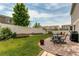 Expansive backyard featuring a white fence, well-manicured lawn, mature trees, and a patio with outdoor seating at 5400 Perth St, Denver, CO 80249