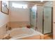 Bright bathroom featuring a soaking tub, glass-enclosed shower, and neutral tile at 5400 Perth St, Denver, CO 80249