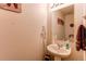 Bright half bathroom featuring a pedestal sink, framed mirror, and wall-mounted towel rack at 5400 Perth St, Denver, CO 80249