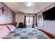 Bedroom featuring a bed, accent chair, mounted TV, and patterned walls at 5400 Perth St, Denver, CO 80249