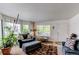 Comfortable living room with a plush armchair, ottoman, area rug, and bright natural light from the large windows at 5400 Perth St, Denver, CO 80249