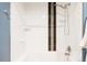 Clean shower with white tile and a decorative dark brown tile striping and modern fixtures at 3415 Florence Way, Denver, CO 80238