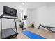 Well-equipped home gym with treadmill, stationary bike, bench, and blue yoga mat on wood floors at 11033 Olathe St, Commerce City, CO 80022