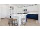 Bright kitchen boasts white cabinets, navy island with breakfast bar seating, and stainless steel appliances at 11033 Olathe St, Commerce City, CO 80022