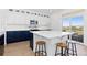 Modern kitchen with white and navy cabinets, island with seating, and sliding glass door at 11033 Olathe St, Commerce City, CO 80022