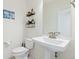 Chic powder room with pedestal sink, decorative shelves, and unique floral floor tiles at 11033 Olathe St, Commerce City, CO 80022