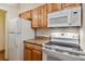 This kitchen boasts wooden cabinets, granite countertops, and standard white appliances at 675 S University Blvd # 205, Denver, CO 80209