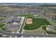 Community aerial view showing homes, a school, and a large green recreational area with a baseball field at 90 Pipit Lake Way, Erie, CO 80516