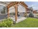 Cozy backyard patio area with a wooden pergola, grill, grass, and a shade, creating an inviting space at 90 Pipit Lake Way, Erie, CO 80516
