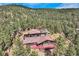 Elevated aerial view of mountain home with deck surrounded by tall pine trees and mountain views at 135 Poorman Rd Rd, Boulder, CO 80302