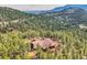 Aerial view of mountain home featuring wrap-around deck, a red roof, and surrounded by pine trees at 135 Poorman Rd Rd, Boulder, CO 80302