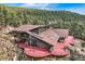 Stunning home with a red wrap-around deck and beautiful mountain views surrounded by evergreen trees at 135 Poorman Rd Rd, Boulder, CO 80302