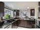 A charming kitchen features dark cabinetry, granite countertops, stainless steel appliances and a window over the sink at 8653 Red Clover Ct, Parker, CO 80134