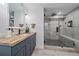 Bathroom with stone tile floor, blue vanity, and large glass shower with modern fixtures at 2364 S Harlan St, Lakewood, CO 80227