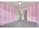 Bright bedroom featuring pink striped walls, neutral carpet, and two entryways for closet and hallway at 559 S Mobile Pl, Aurora, CO 80017