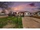 Charming single-story home with stone accents, a well-maintained lawn, and a concrete driveway at dusk at 1293 S Perry St, Denver, CO 80219