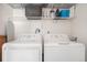 Bright laundry area with white washer and dryer and shelving above for storage and organization at 17297 Wilde Ave # 205, Parker, CO 80134