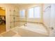 Bright bathroom with a soaking tub, glass shower, and neutral-toned tile at 15484 E 115Th Ave, Commerce City, CO 80022