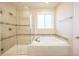 Bathroom showcasing a soaking tub, glass shower, and neutral-toned tile at 15484 E 115Th Ave, Commerce City, CO 80022