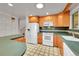 Bright kitchen with white appliances, wooden cabinetry, and a breakfast bar at 2826 S Lamar St, Denver, CO 80227