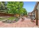 Inviting backyard featuring stone patio, swing bench, mature trees, and vibrant flower beds at 21107 Hawthorne Ln, Parker, CO 80138