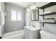 Modern bathroom featuring a shower-tub combo, gray tiled walls, updated vanity and black shelving at 3285 S Delaware St, Englewood, CO 80110