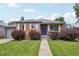 Charming brick home with lush landscaping, gray garage, and a bright blue front door at 3285 S Delaware St, Englewood, CO 80110