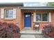 Close-up of front porch featuring a brick facade, blue door, and a decorative chair at 3285 S Delaware St, Englewood, CO 80110