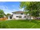 Large backyard showing a two-story home with a patio, lush lawn, and mature trees at 5853 S Havana Ct, Englewood, CO 80111
