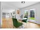 Bright dining area with hardwood floors and stylish green chairs, leading to an open-concept kitchen and living space at 5853 S Havana Ct, Englewood, CO 80111