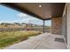 Covered patio with stone columns, offering a view of the well-manicured lawn and community beyond at 1660 Candleflower Dr, Castle Pines, CO 80108