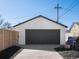 A detached white garage with a dark gray door and concrete driveway at 4947 Saint Paul St, Denver, CO 80216