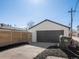 Detached white garage with a dark gray door and concrete driveway with trash bins at 4947 Saint Paul St, Denver, CO 80216