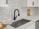 Close-up of kitchen sink with stainless steel sink, white countertops, and stylish black faucet at 4947 Saint Paul St, Denver, CO 80216