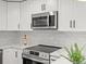 Bright kitchen with stainless steel appliances, white cabinets, white countertops, and stylish backsplash at 4947 Saint Paul St, Denver, CO 80216