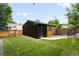Modern shed in the backyard featuring black siding and natural wood, complemented by green grass at 863 S Race St, Denver, CO 80209