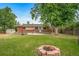 Backyard view features a patio, mature tree, fire pit, wooden fence, and lush green grass at 8051 S Kendall Blvd, Littleton, CO 80128