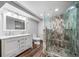 Bathroom with mosaic tile shower, wood-look floor, and double sink vanity at 8051 S Kendall Blvd, Littleton, CO 80128