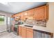 This is a kitchen featuring oak cabinetry, stainless steel appliances, and tile backsplash at 8051 S Kendall Blvd, Littleton, CO 80128