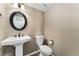 Cozy powder room features pedestal sink, round mirror, and a modern toilet at 938 W Peakview Cir, Littleton, CO 80120